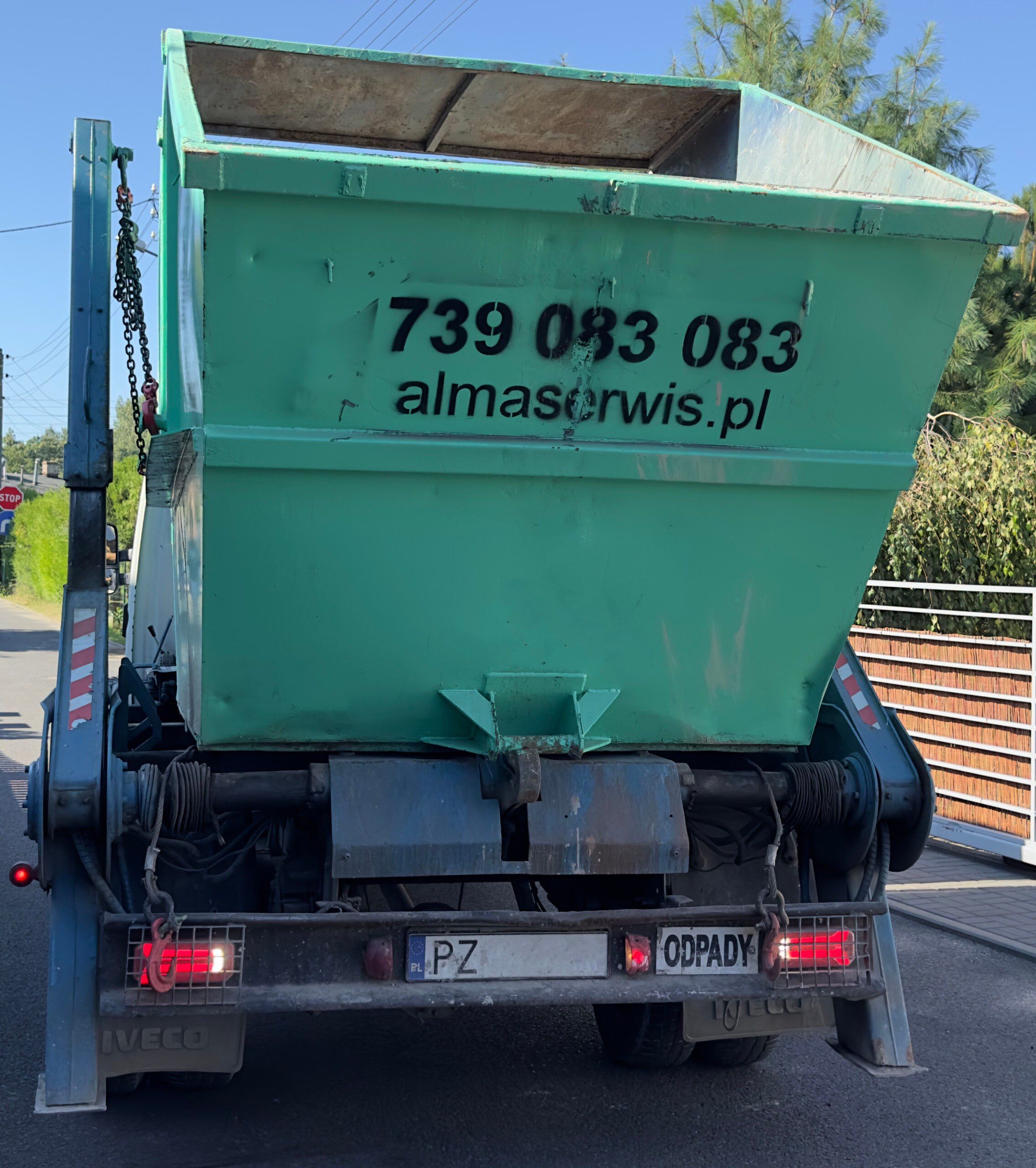 Bramowiec Alma Serwis z podniesionym zielonym kontenerem, widok z tyłu