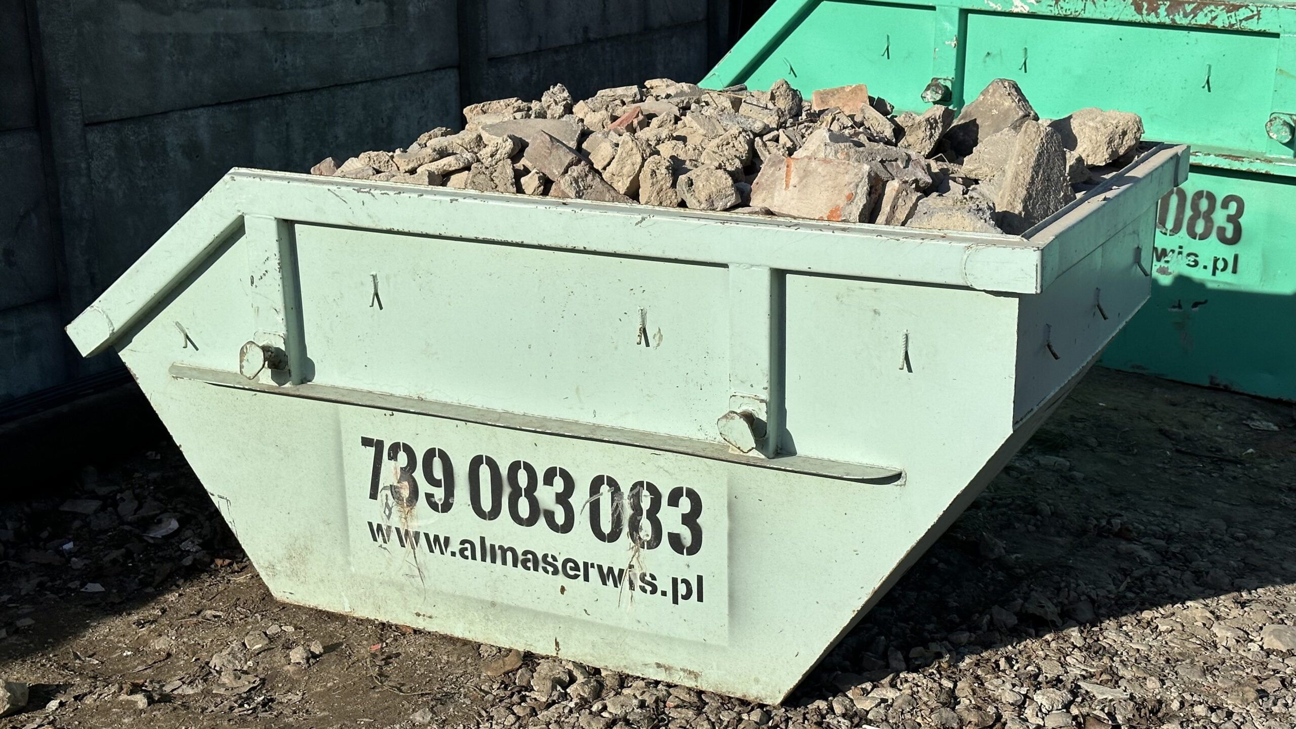 Jasnozielony kontener Alma Serwis z gruzem betonowym na placu