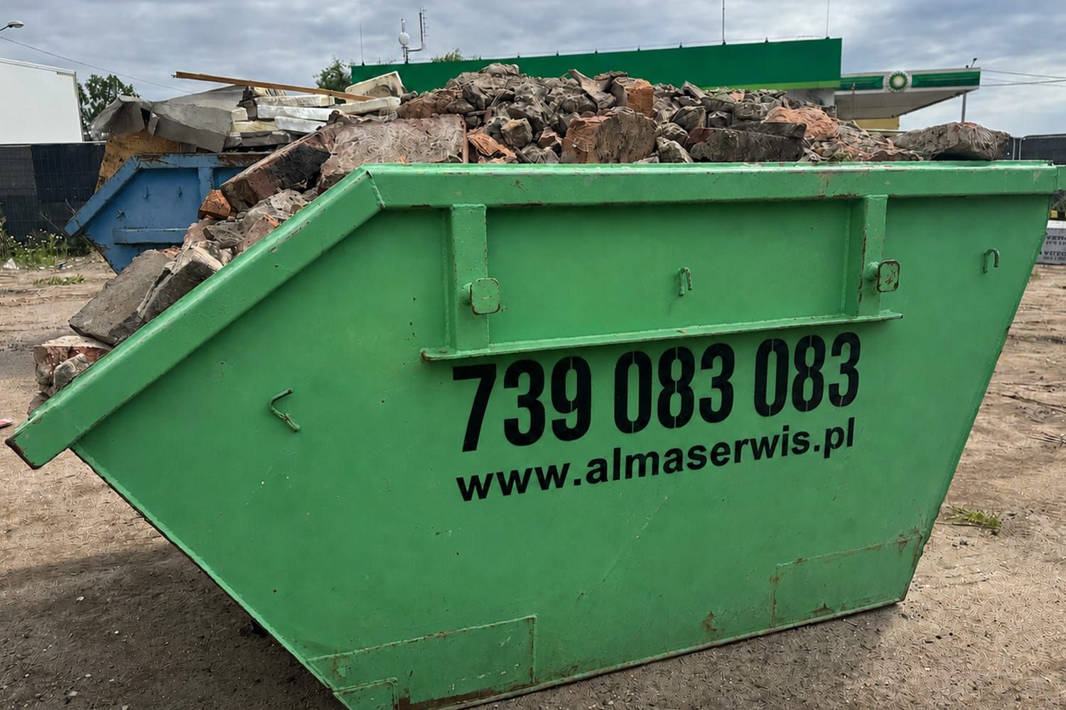 Zielony kontener Alma Serwis wypełniony gruzem ceglanym i ceramicznym